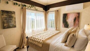 Un dormitorio con cama, una silla, un ventilador de techo y una ventana con cortinas.