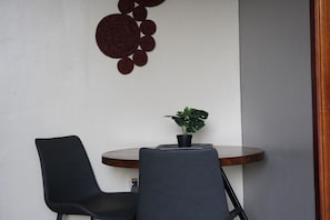 A corner of a room with a round table, two chairs, and a potted plant. - A Comfy 1-bedroom apartment in central Kampala perfect for your stay! (Kampala)