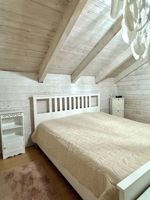 A bedroom with a white bed, a nightstand, a dresser, and a wooden ceiling. - Starting Feb. 27: Vacation rental on the edge of the forest; dogs welcome upon request; not centrally located (Halsbach)