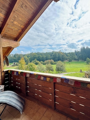 A wooden balcony with a view of a green landscape and a cloudy sky. - Starting Feb. 27: Vacation rental on the edge of the forest; dogs welcome upon request; not centrally located (Halsbach)