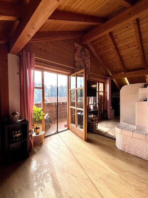 A wooden interior with a sliding glass door leading to an outdoor area, a fireplace, and a shelf with various items. - Starting Feb. 27: Vacation rental on the edge of the forest; dogs welcome upon request; not centrally located (Halsbach)
