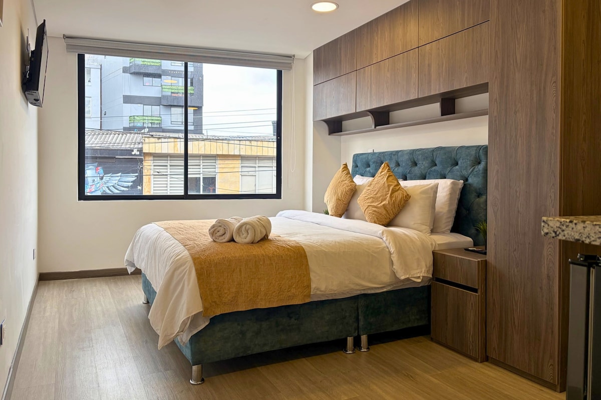Un dormitorio moderno con una cama grande, vistas de la ciudad a través de una ventana y armarios empotrados de madera.