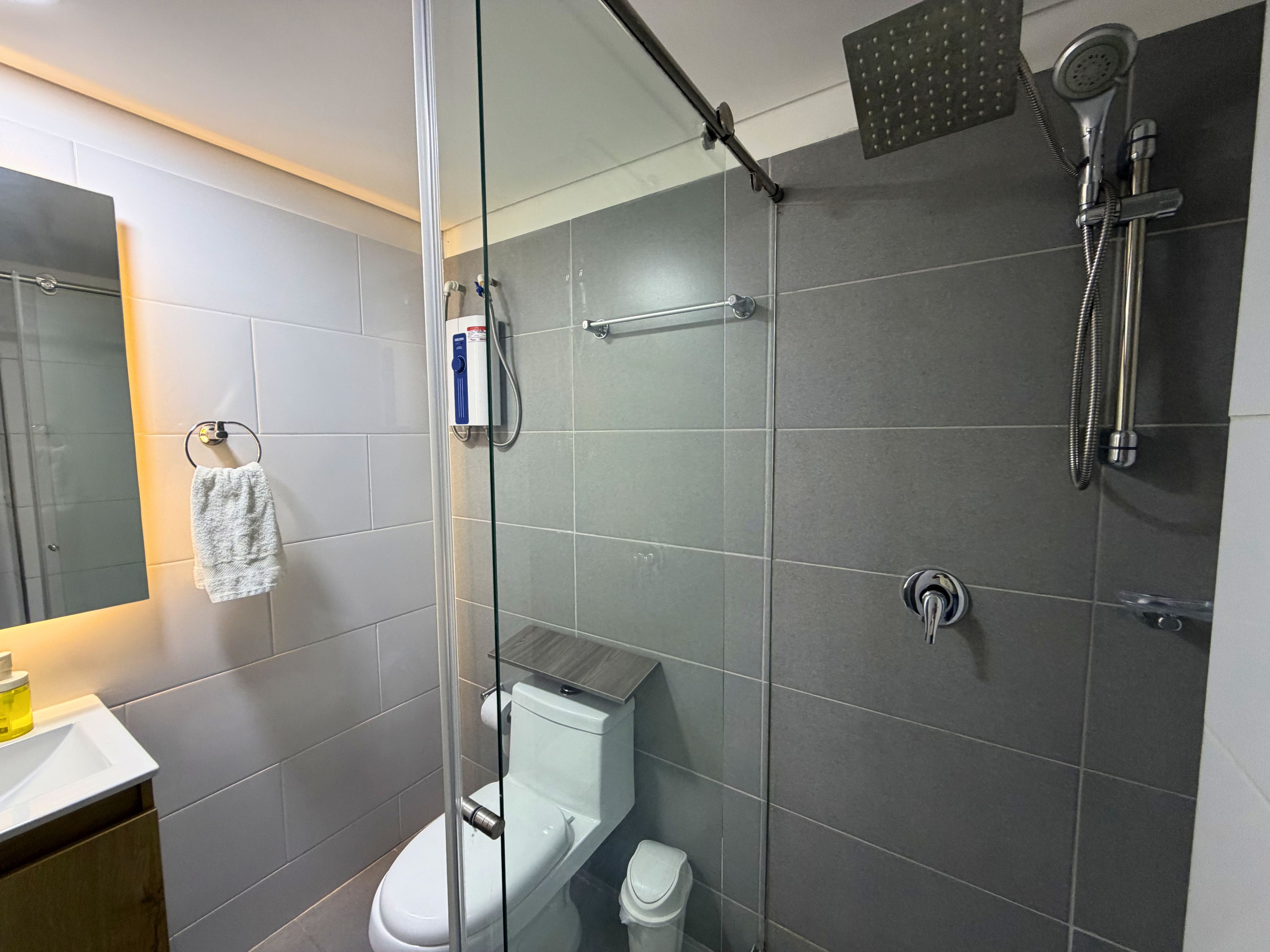 A modern bathroom with a glass shower enclosure, a toilet, and a sink.