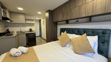 Une chambre d’hôtel avec un lit, une kitchenette et vue sur le couloir.