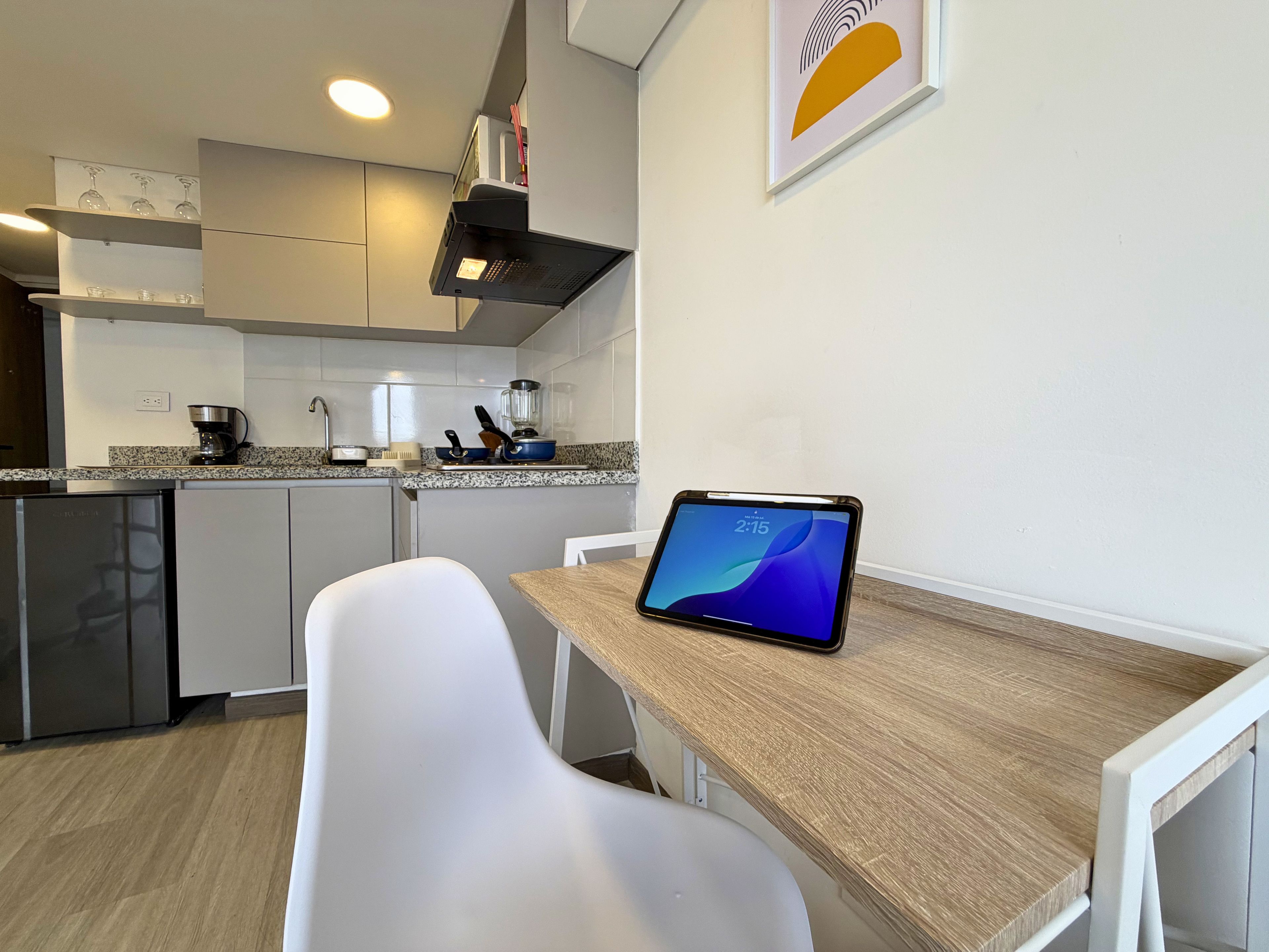 Una cocina moderna con una tableta en la encimera, una cafetera y una licuadora.