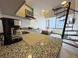 A modern kitchen with granite countertops, a coffee maker, and a stove. - Nook Galerías by Renteo (Bogotá)