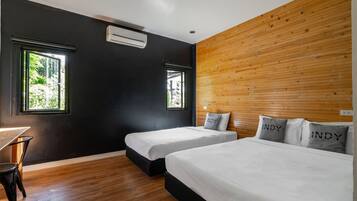 A hotel room with two beds, a desk, and a window.