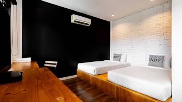 Een moderne hotelkamer met twee bedden, een houten tafel, een zwarte muur en een muur van witte bakstenen.
