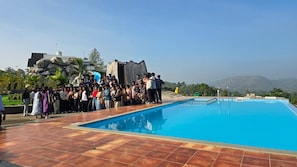 A swimming pool with a tiled deck, surrounded by a crowd of people.