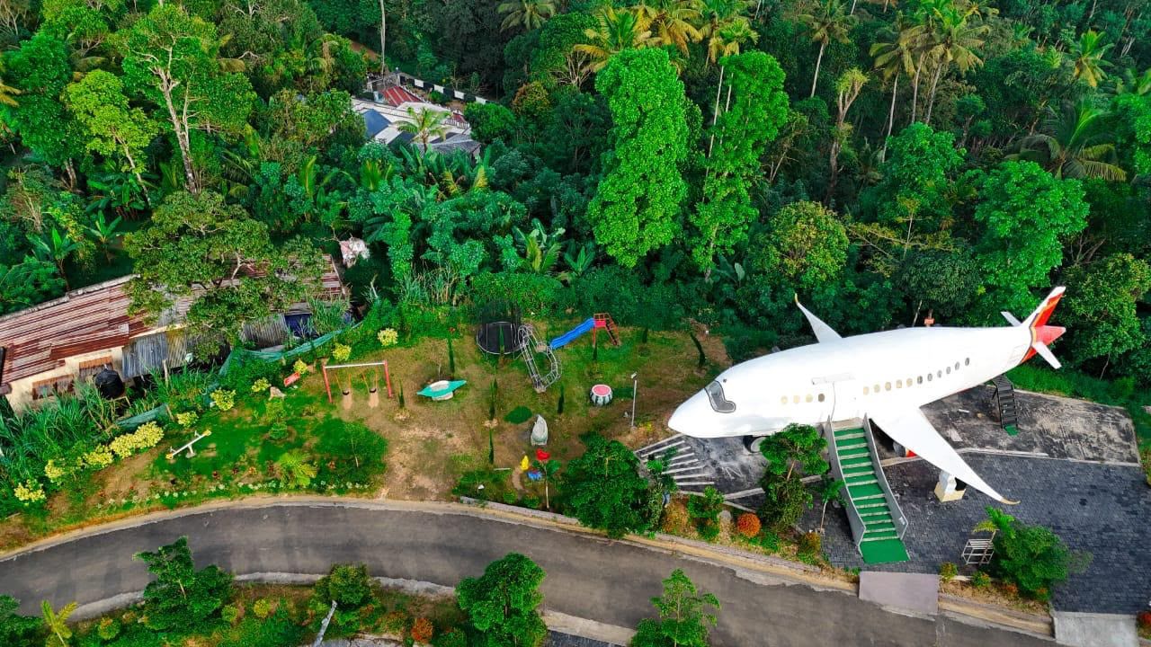 Un avión estacionado en una pista, rodeado de densa vegetación tropical.
