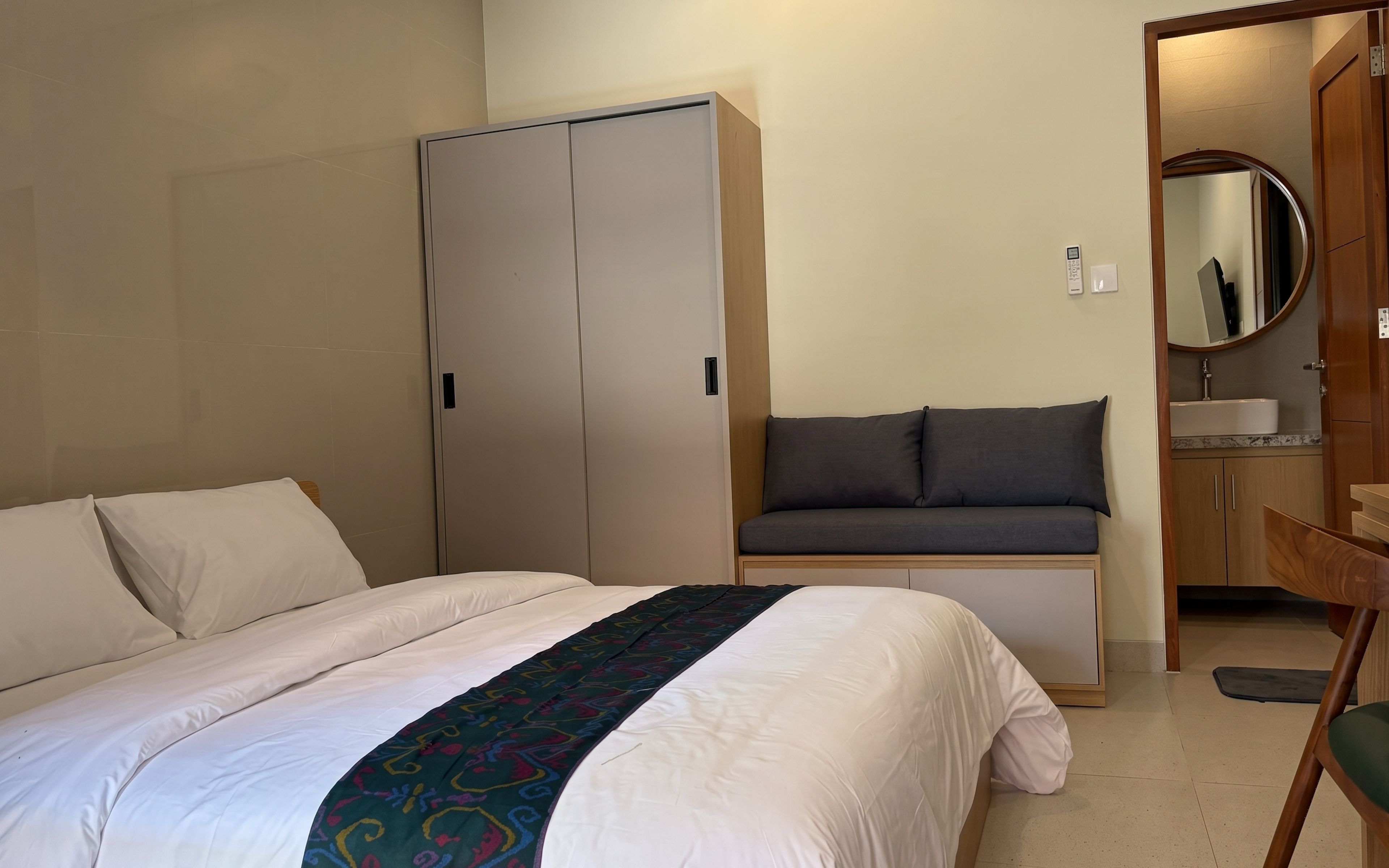 A hotel room with a bed, a wardrobe, a seating area, and a bathroom.