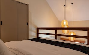 Un dormitorio con una cama, cabecera de madera y una lámpara colgante.