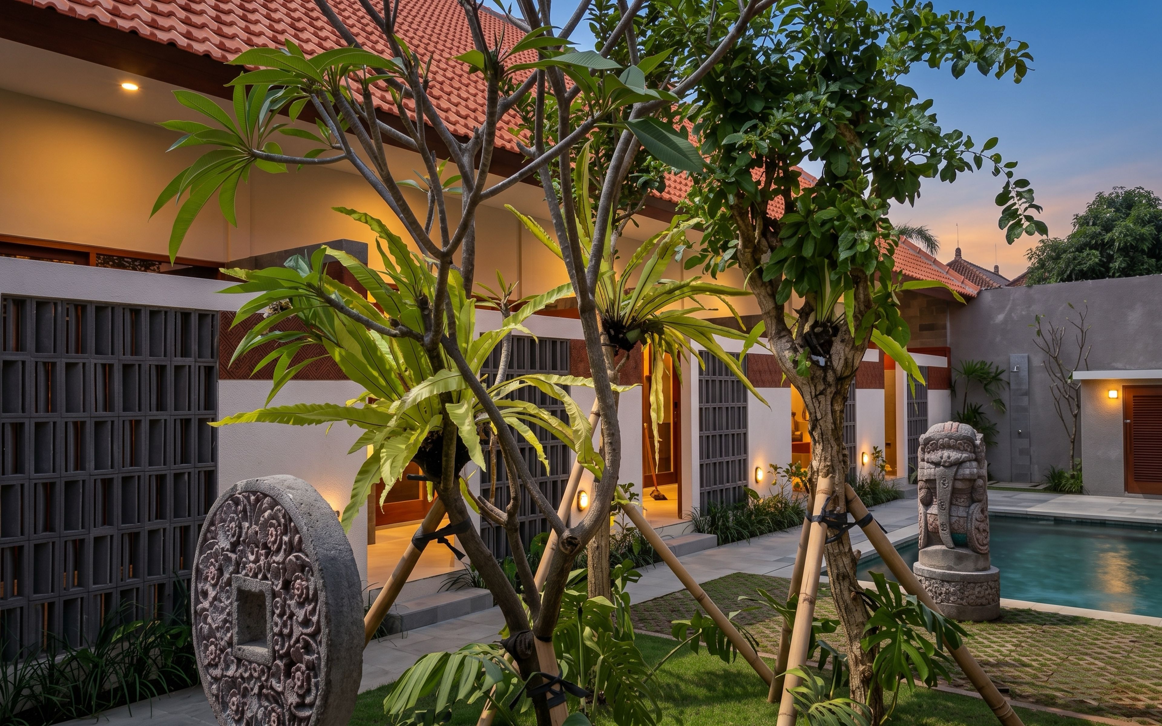 A traditional building with a tiled roof, surrounded by lush greenery and a swimming pool.