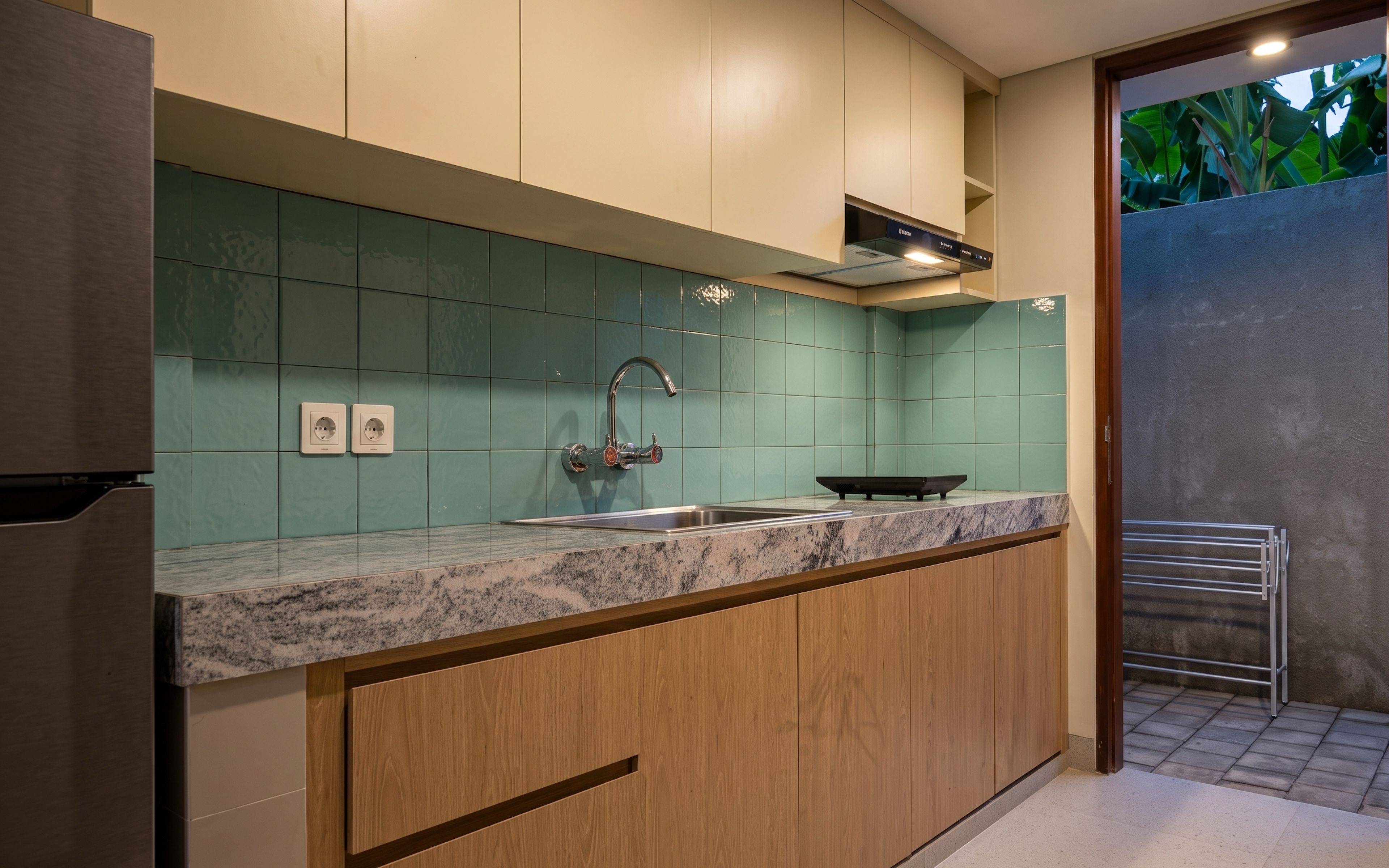 Una cocina moderna con encimera de granito, pileta de acero inoxidable y muebles de madera.