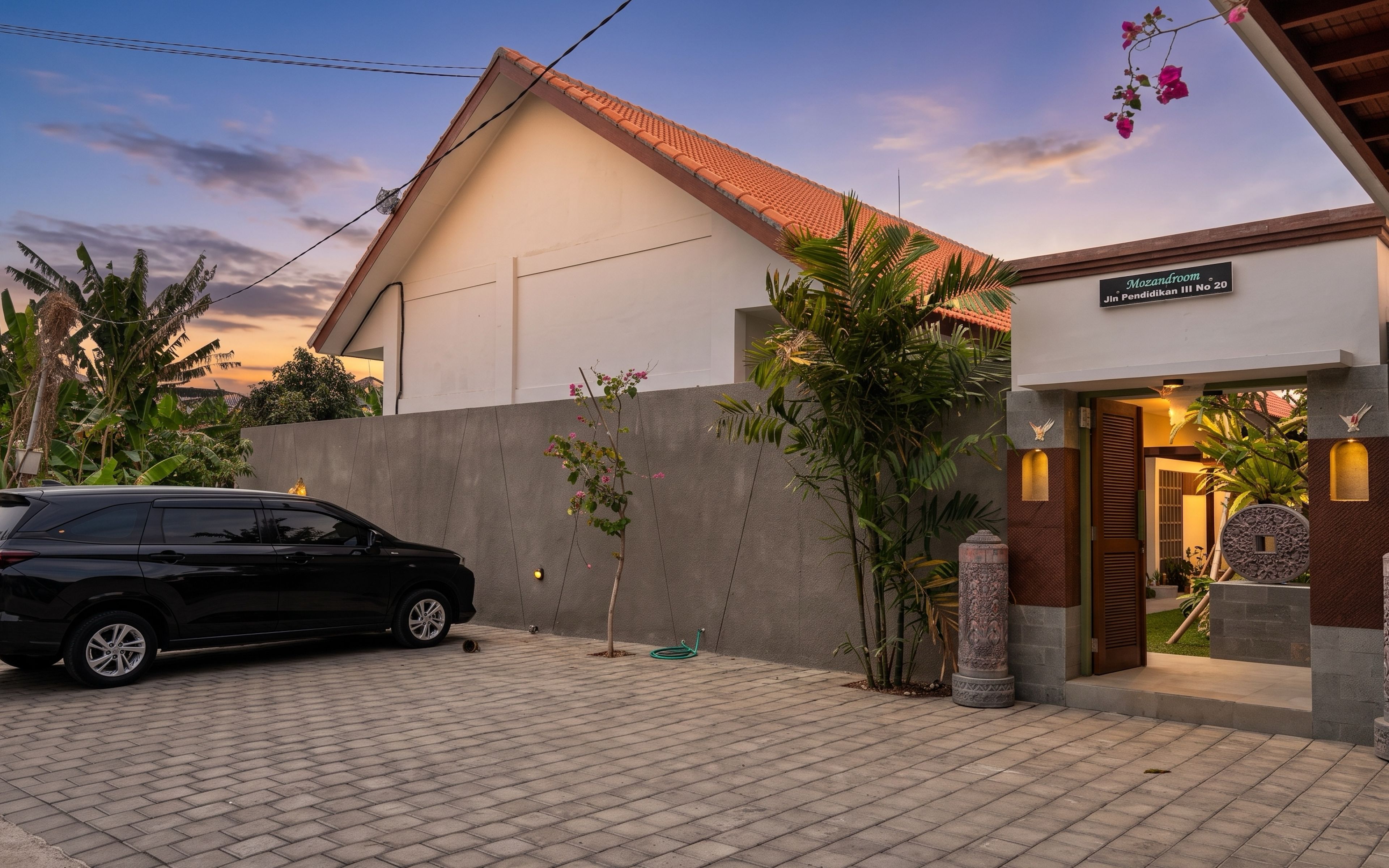A modern building with a tiled roof, a paved driveway, and a car parked in front.