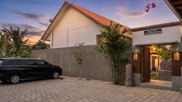 A modern building with a tiled roof, a paved driveway, and a car parked in front.