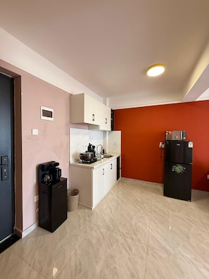 A compact kitchen with a coffee machine, a stove, and a refrigerator. - TALANTA SKYLINE ONE BEDROOM ALONG NGONG ROAD, NEAR JUNCTION MALL (Nairobi)