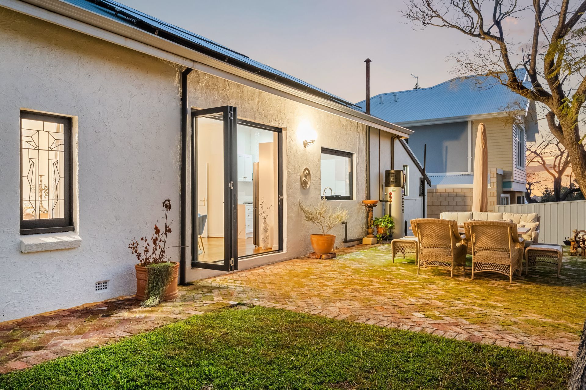 Una casa con patio, mobili da esterno e giardino.