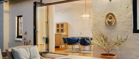 An open-plan living area with a dining table, chairs, and a potted plant.