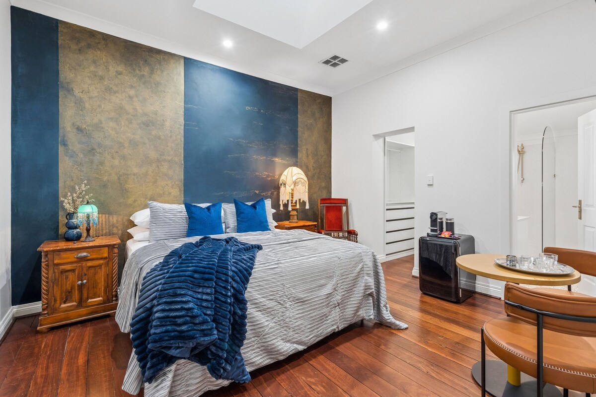 Un dormitorio moderno con una cama grande, una mesita de noche, una lámpara, una silla y una pequeña mesa.