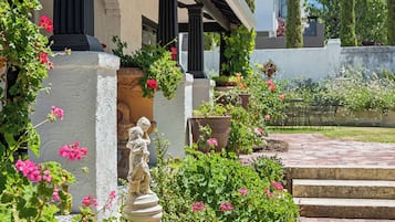 A garden with a statue, potted plants, and a stone pathway.