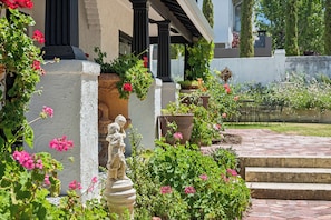 A garden with a statue, potted plants, and a stone pathway.