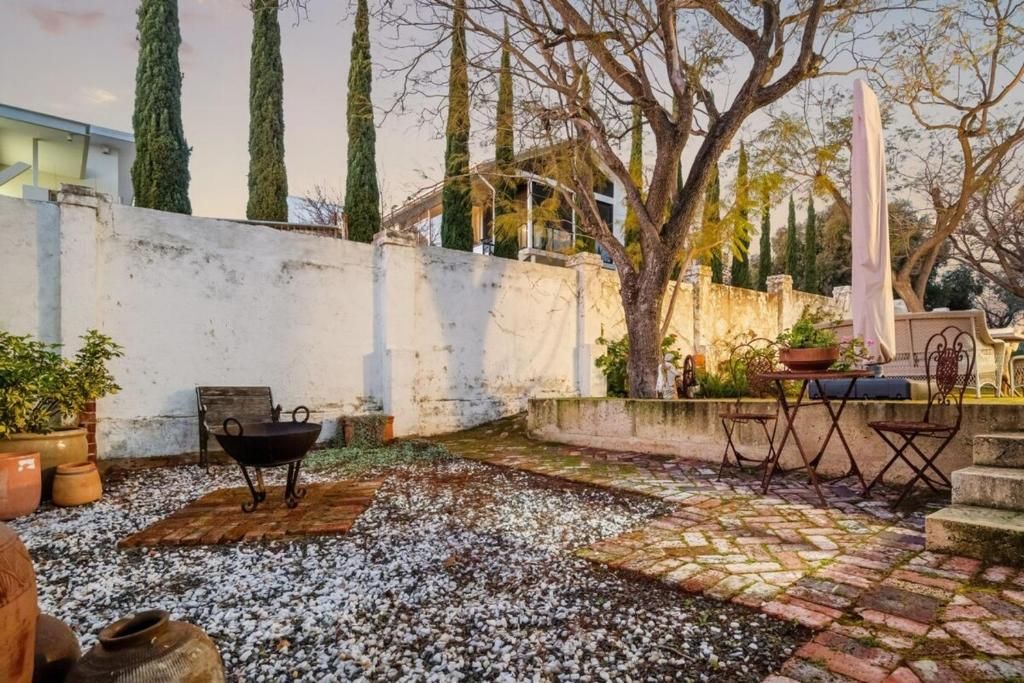 Un patio al aire libre con piso de piedra rústica, una parrilla de metal y un conjunto de asientos con sillas y una mesa de metal.