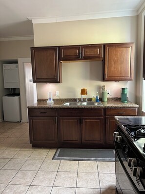 A kitchen with wooden cabinets, a sink, a stove, and a refrigerator. - Cozy Retreat (St. Louis)