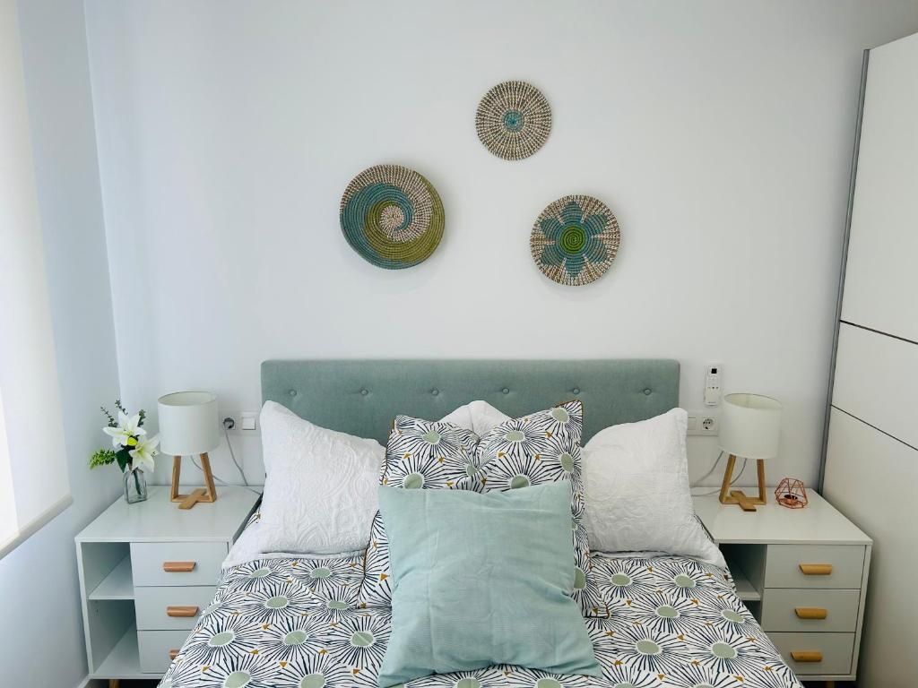 Un dormitorio con una cama, dos mesitas de noche y decoración en la pared.