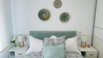Un dormitorio con una cama, dos mesitas de noche y decoración en la pared.