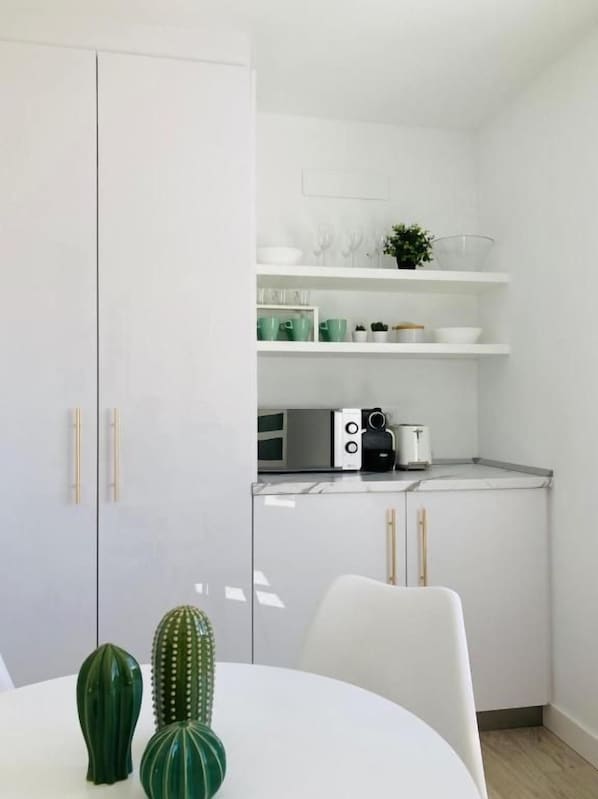 Una cocina moderna con armarios blancos, una mesa de comedor blanca y una decoración de cactus.