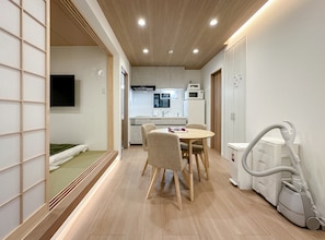 A modern interior with a dining area, kitchen, and a vacuum cleaner. - HANASTAY MUKAI MIGIWA & SUZU (Osaka)