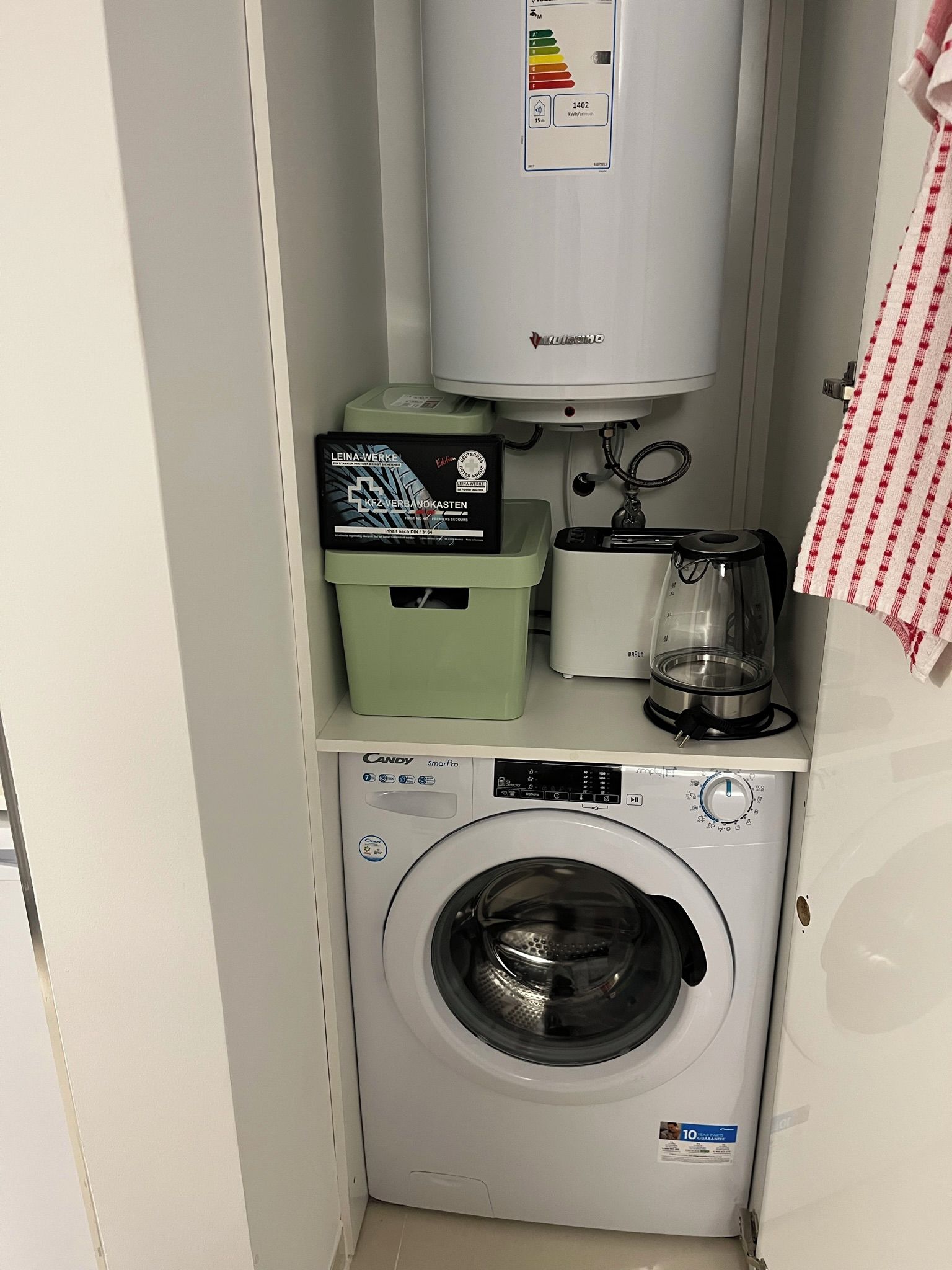Ein kleiner Waschbereich mit Waschmaschine, Kühlschrank und Kaffeemaschine.