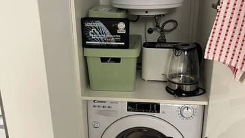 Ein kleiner Waschbereich mit Waschmaschine, Kühlschrank und Kaffeemaschine.