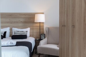 Une chambre d’hôtel avec un lit, une chaise, une table de chevet et une lampe.
