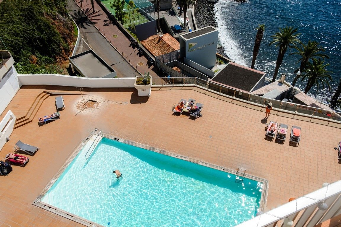 Une piscine sur le toit offrant une vue sur l’océan, entourée de chaises longues et de parasols.