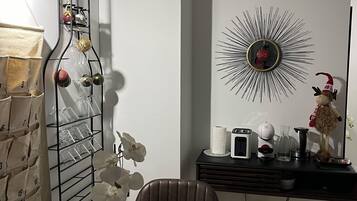 A modern dining area with a marble table, a vase with a flower, a wine rack, and a decorative mirror.