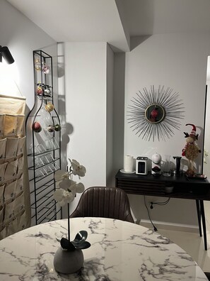 A modern dining area with a marble table, a vase with a flower, a wine rack, and a decorative mirror. - Atlantic Calling - first Line with stunning Sea View and own parking space (Funchal)
