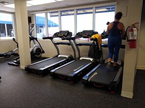 A gym with treadmills, a stationary bike, and a water bottle on one of the machines. - Bright studio in peaceful Sunny Isles Beach with AC and gym STR01721 (Sunny Isles Beach)