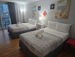 Une chambre d’hôtel avec deux lits, un balcon et des œuvres d’art aux murs.