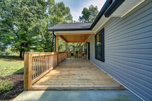 A covered wooden deck leading to a house with a dark roof and light siding. - Peaceful New 3BR East Tennessee Retreat- Fire Pit - Deck- Garage (Sweetwater)