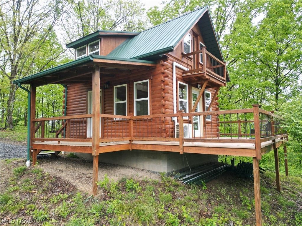 Een vakantiehuis in blokhutstijl met een balkon en een overdekte veranda.