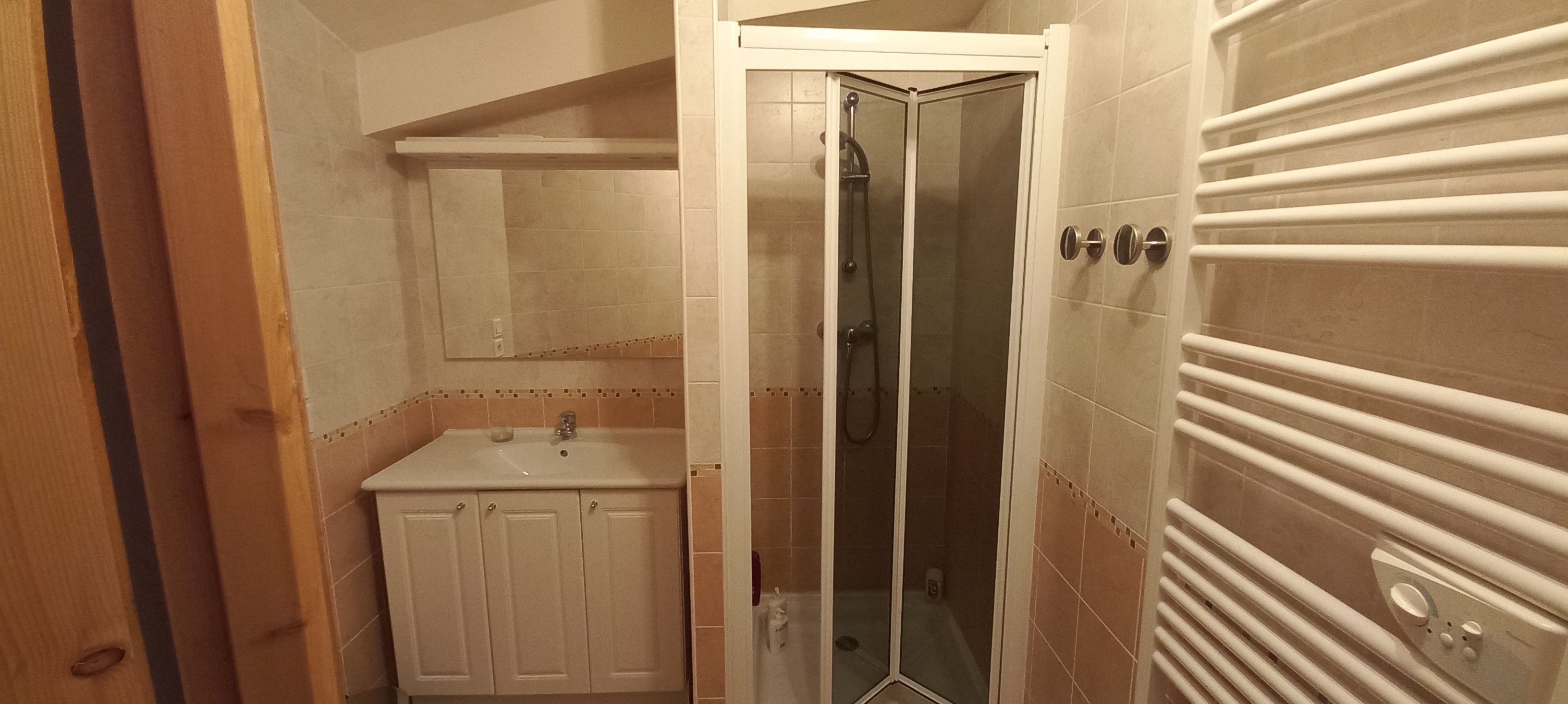 Un baño con ducha, lavamanos y armarios.