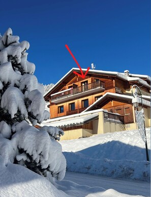 A wooden chalet with a balcony, surrounded by snow-covered trees. - Duplex apartment at the base of the slopes, sleeps 6, 50 m²—Les Saisies—Les Contamines-Montjoie (Hauteluce)