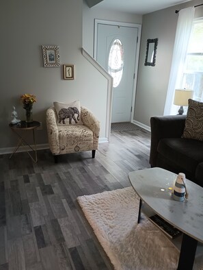 Un salon comprenant un fauteuil à motifs, un canapé, une table basse et un tapis.
