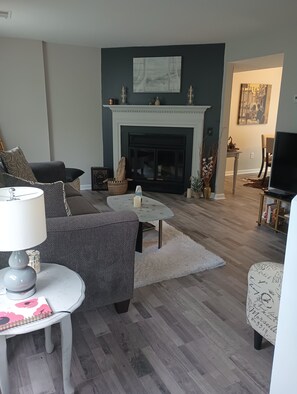 Un salon avec une cheminée, un canapé, une table basse et un téléviseur.