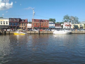 A waterfront with boats docked, buildings with commercial signage, and a clear sky. - 3-bedroom Home Away From Home.  More than a rental — it's an experience. (Annapolis)
