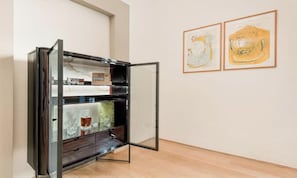 Une pièce dotée d’une vitrine, d’un plancher en bois et de deux œuvres d’art encadrées accrochées au mur.