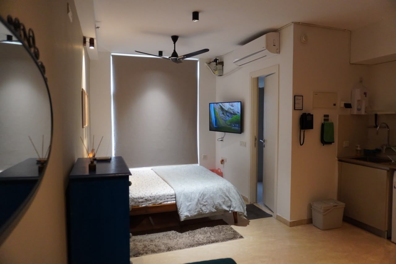Ein Schlafzimmer mit einem Bett, einem Deckenventilator, einem Fernseher und einer Küchenzeile.