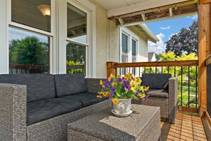 A covered outdoor seating area with a sofa and a potted plant.